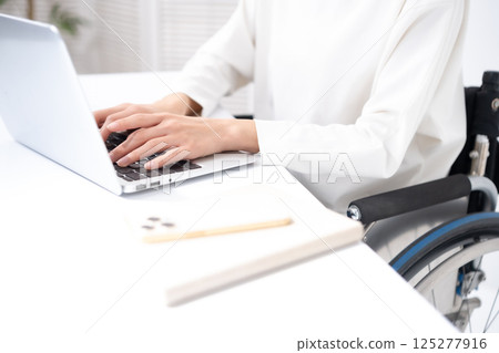 坐在輪椅上、手邊有電腦的女人 125277916