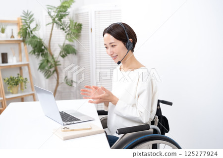 Woman in wheelchair online headset Woman in wheelchair online headset 125277924