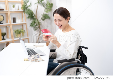 Woman in wheelchair, money, bankbook, smile 125277950