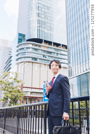 A man using a smartphone in an office district A man using a smartphone in an office district 125277958
