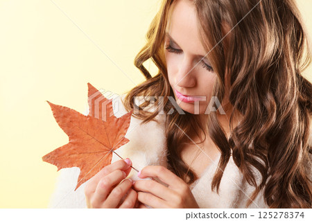 Pretty autumnal girl with maple leaf in hand 125278374