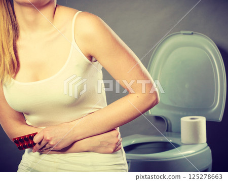 Woman suffer from belly pain holds pills in toilet Woman suffer from belly pain holds pills in toilet 125278663
