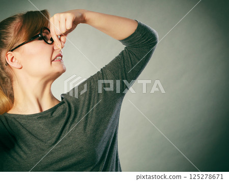 Nerdy girl holding nose. Nerdy girl holding nose. 125278671