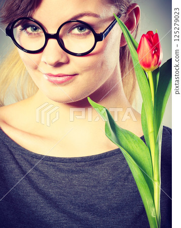 Seducive nerdy girl holding tulip. Seducive nerdy girl holding tulip. 125279023