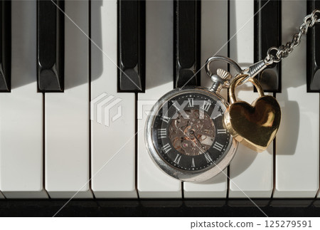 Antique pocket watch (A retro pocket watch) with Golden heart shaped love padlock on Piano keys background. Antique pocket watch (A retro pocket watch) with Golden heart shaped love padlock on Piano keys background. 125279591