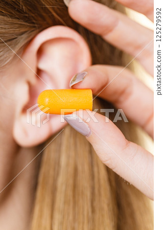 Woman putting earplugs Woman putting earplugs 125279592