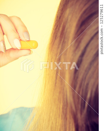 Woman holding protective earplugs Woman holding protective earplugs 125279611