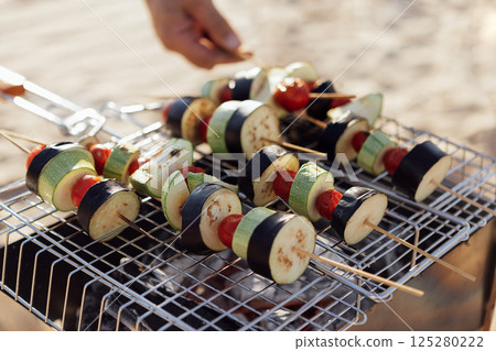 A young man in a summer casual outfit is having a barbecue on beach. 125280222