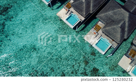 Aerial view of luxurious overwater villas with thatched roofs. 125280232