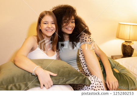Cute teenagers of different races in casual clothes have fun on the bed in the bedroom. 125280253