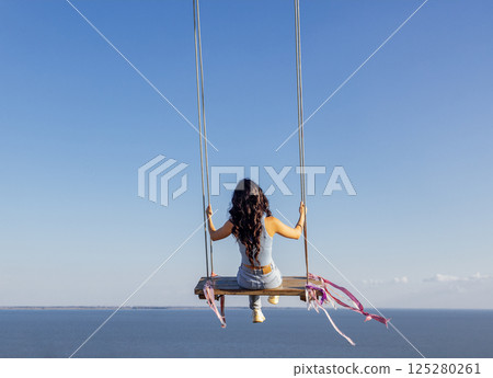 Attractive Asian girl in casual clothes swinging on an outdoor swing Attractive Asian girl in casual clothes swinging on an outdoor swing 125280261