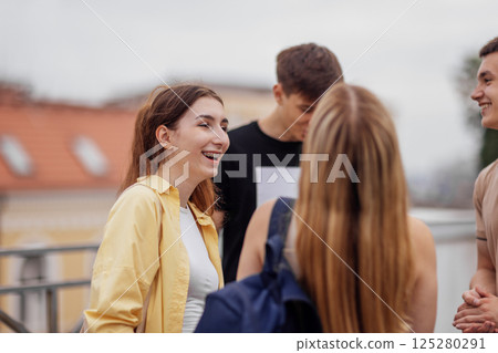 Four teenagers in casual clothes chat and laugh on the roof of the house Four teenagers in casual clothes chat and laugh on the roof of the house 125280291