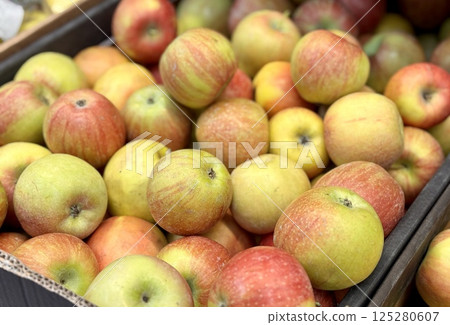 Box filled with fresh natural bio organic red yellow green apples placed on counter in local food market. Close-up Box filled with fresh natural bio organic red yellow green apples placed on counter in local food market. Close-up 125280607