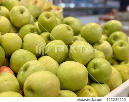 Box filled with fresh natural bio organic green yellow coloured apples placed on counter in local food market. Close-up. 125280613
