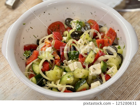 A vibrant Mediterranean salad featuring tomatoes, cucumbers, olives, and feta cheese, perfect for any meal. Close-up. 125280631