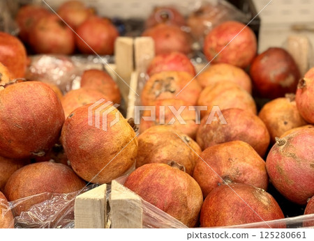 Lots of ripe red pomegranates on a market counter for sale on sale in vegetable stand display at supermarket show organic food, vegetarian food, healthy food. Close-up 125280661