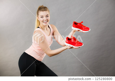 Happy woman presenting sportswear trainers shoes 125280800