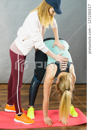 Woman in sportswear doing workout with trainer 125280817