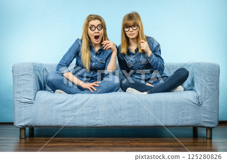 Two shocked women holding fake eyeglasses on stick Two shocked women holding fake eyeglasses on stick 125280826