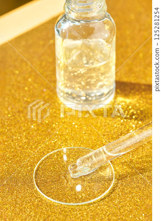 Clear serum dropper with golden background for skincare and beauty treatments 125281254