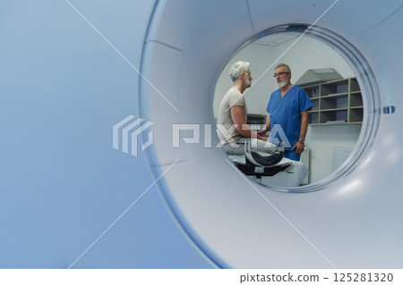 Doctor explaining CT scan results to patient in hospital setting Doctor explaining CT scan results to patient in hospital setting 125281320