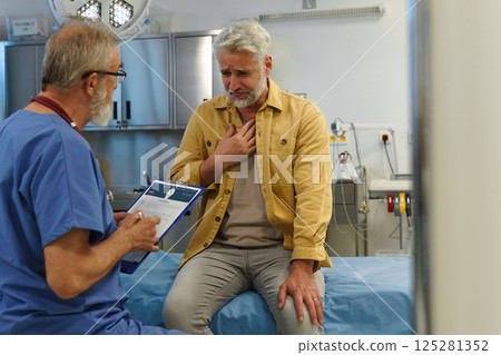 Patient sitting on examination table, describing chest pain to doctor. 125281352