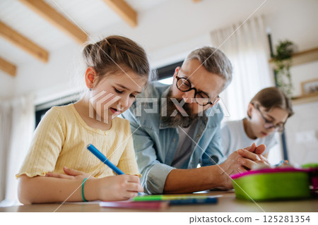 Father helping his daughters with homework. Father helping his daughters with homework. 125281354