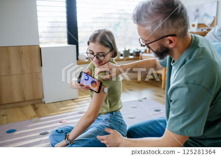 Diabetic girl with a CGM sensor on her arm. 125281364