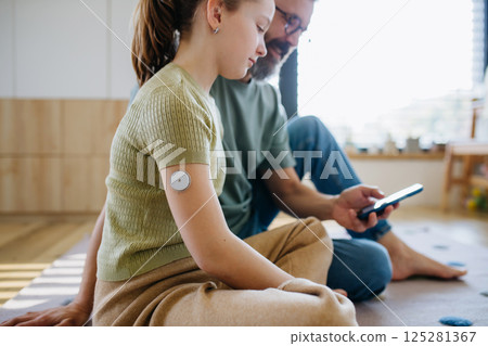 Diabetic girl with a CGM sensor on her arm. 125281367