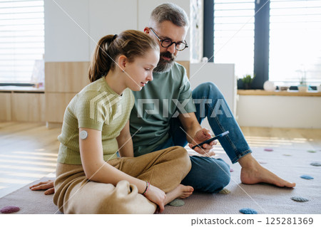 Diabetic girl with a CGM sensor on her arm. 125281369
