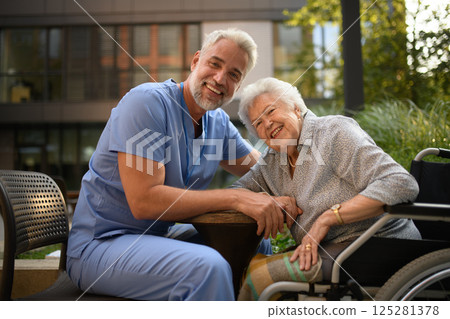 Male caregiver talking with senior woman in wheelchair. Male caregiver talking with senior woman in wheelchair. 125281378