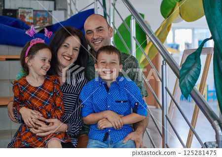 Portrait of a happy family. Photo of parents with children in a modern preschool classroom. Selective focus Portrait of a happy family. Photo of parents with children in a modern preschool classroom. Selective focus 125281475