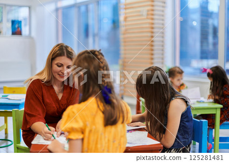 Creative kids during an art class in a daycare center or elementary school classroom drawing with female teacher. 125281481