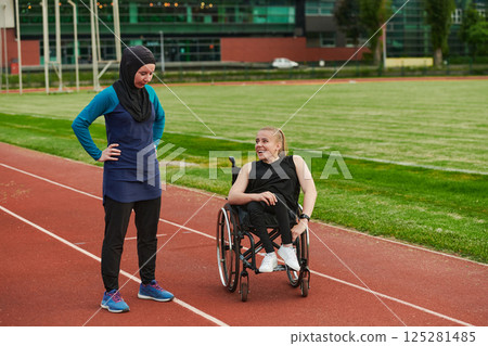 A Muslim woman wearing a burqa resting with a woman with disability after a hard training session on the marathon course 125281485