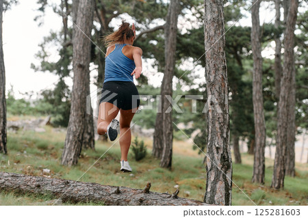 Fearless Woman Conquering Wooden Obstacles in the Dangerous Forest Terrain. 125281603