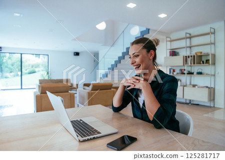 Woman sitting in living room using laptop looking at cam talk by video call with business friend relatives, head shot. Job interview answering questions Woman sitting in living room using laptop looking at cam talk by video call with business friend relatives, head shot. Job interview answering questions 125281717