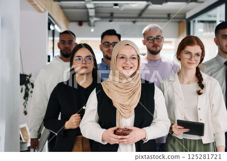 A group of business professionals standing together, taking a well-deserved break from their busy workday, showcasing camaraderie, teamwork, and a moment of relaxation in their dynamic workplace 125281721
