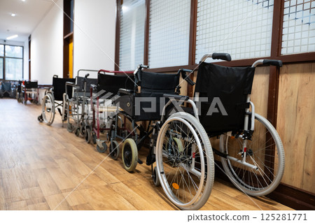 A row of wheelchairs neatly lined up in a hospital corridor, ready for patients in need of mobility assistance A row of wheelchairs neatly lined up in a hospital corridor, ready for patients in need of mobility assistance 125281771