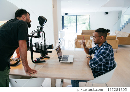 A cameraman talking with an African American man as they preparing to shoot a commercial video. High quality photo 125281805