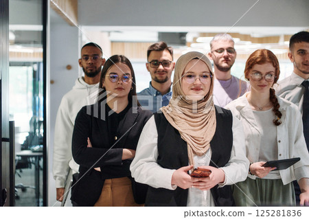 A group of business professionals standing together, taking a well-deserved break from their busy workday, showcasing camaraderie, teamwork, and a moment of relaxation in their dynamic workplace A group of business professionals standing together, taking a well-deserved break from their busy workday, showcasing camaraderie, teamwork, and a moment of relaxation in their dynamic workplace 125281836