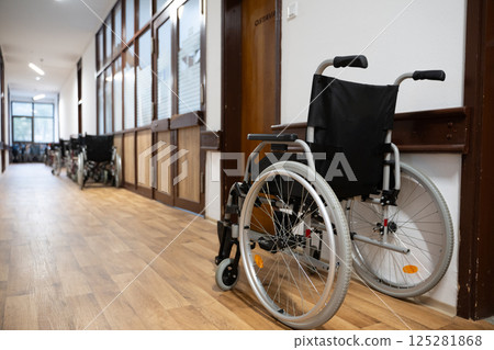 A row of wheelchairs neatly lined up in a hospital corridor, ready for patients in need of mobility assistance A row of wheelchairs neatly lined up in a hospital corridor, ready for patients in need of mobility assistance 125281868