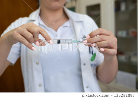 A focused nurse in a white lab coat carefully prepares a syringe for an injection in a professional healthcare environment. A focused nurse in a white lab coat carefully prepares a syringe for an injection in a professional healthcare environment. 125281895