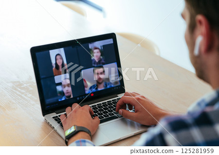 A freelancer sitting at a table in a modern living room, with headphones using a laptop for business video chat, conversation with friends and entertainment 125281959
