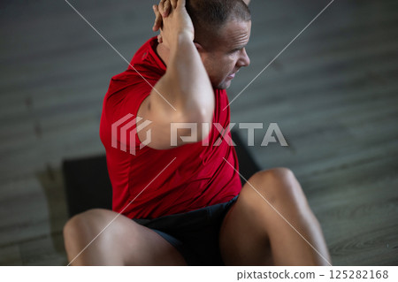 A muscular man performing crunches in the gym, focusing on building core strength and achieving his fitness goals A muscular man performing crunches in the gym, focusing on building core strength and achieving his fitness goals 125282168