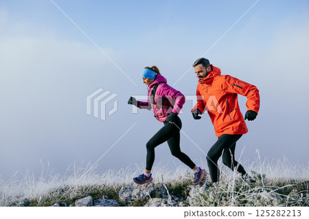 Trail running couple man and woman running on a mountain path 125282213