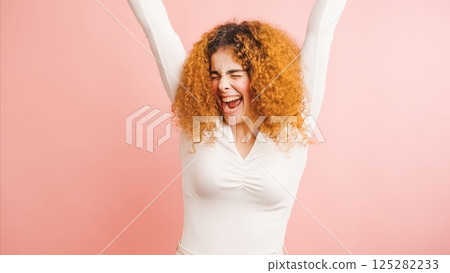 Enthusiastic young woman celebrating with arms raised and eyes closed Enthusiastic young woman celebrating with arms raised and eyes closed 125282233