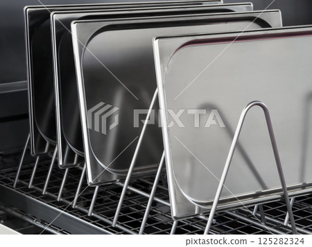 Stainless steel trays arranged neatly on a rack in a modern kitchen setting during daytime 125282324