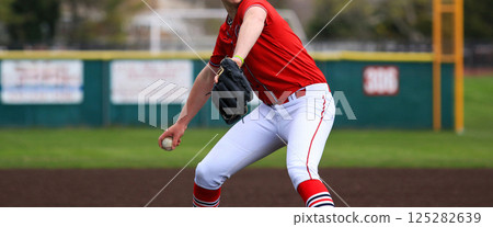 Pitcher winding up to throw the ball while pitching during a high school baseball game 125282639