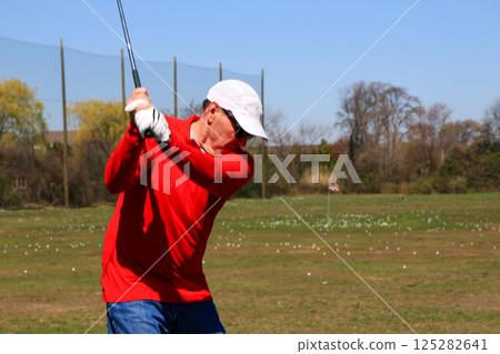 Practicing Golf Swings at a Sunny Driving Range With Plenty of Space Practicing Golf Swings at a Sunny Driving Range With Plenty of Space 125282641