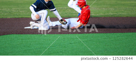 Runner Sliding into Second Base with the Short Stop Trying to Apply the Tag During a Baseball Game Runner Sliding into Second Base with the Short Stop Trying to Apply the Tag During a Baseball Game 125282644